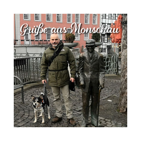 Joachim Ritz steht mit seiner Hündin neben einer lebensgroßen Bronzefigur im Zentrum der wunderschönen Stadt Monschau.